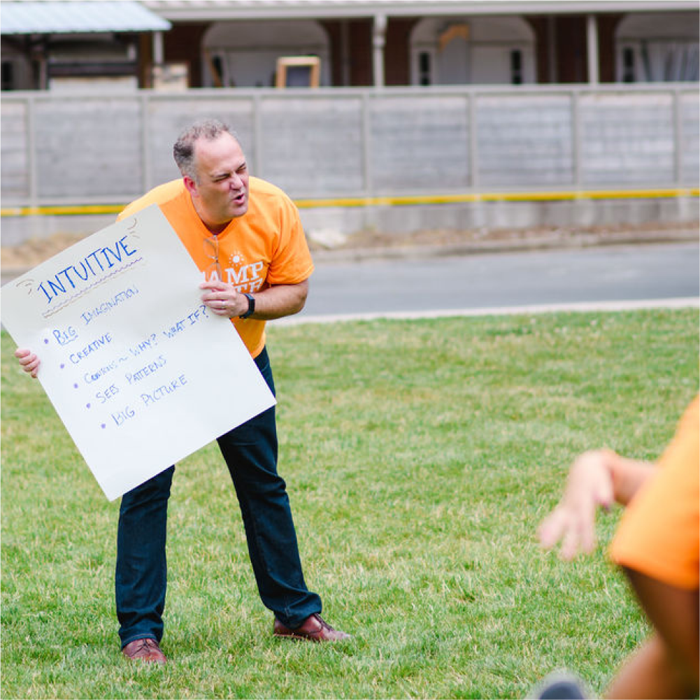 Girls on the run coach holding sign reading intuitive